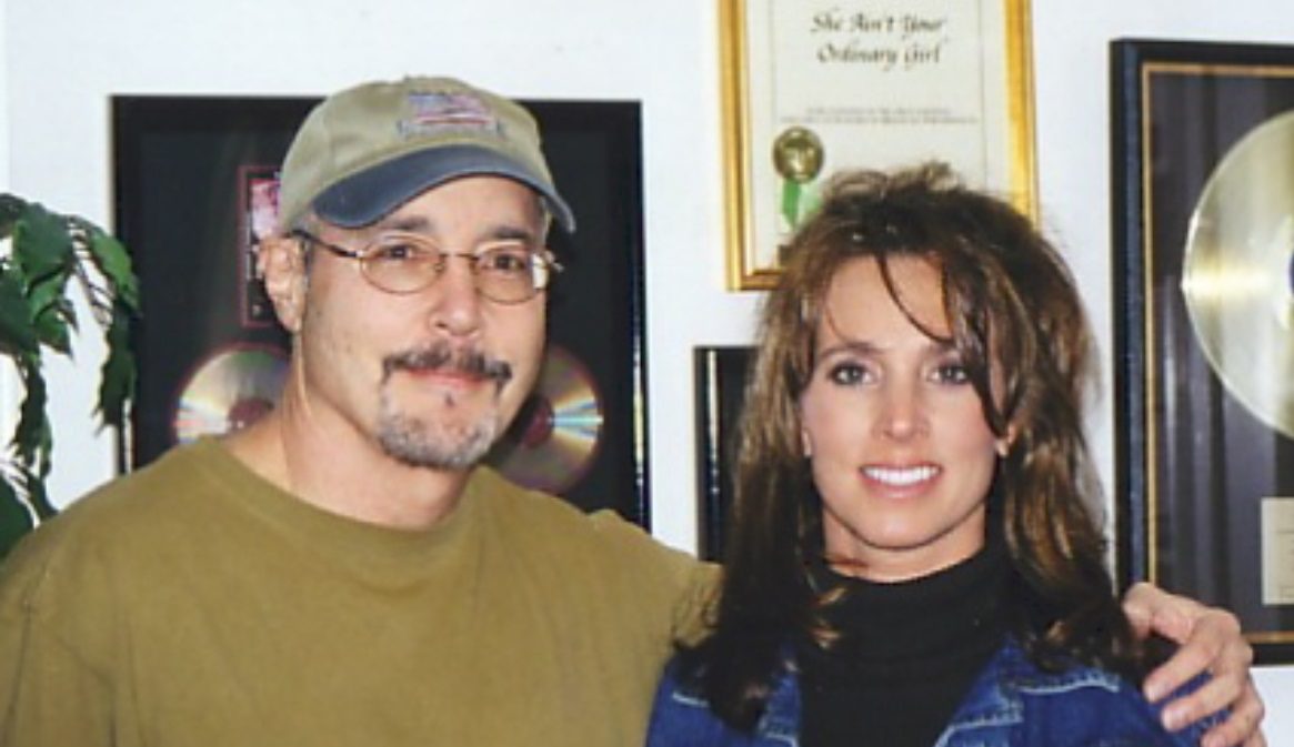 Robert Jason and Tammy in front of his gold records and the framed &lsquo;She Ain&rsquo;t Your Ordinary Girl&rsquo; award